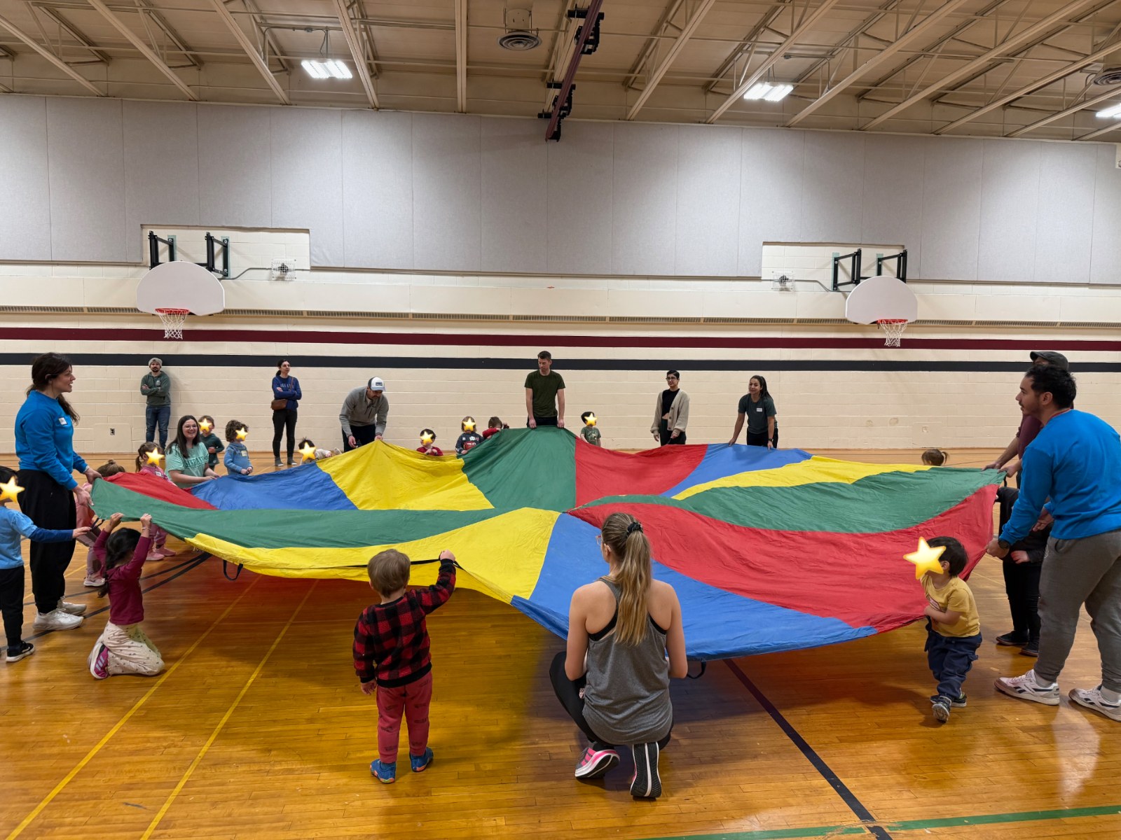 Kids and coaches playing a parachute game in the gym